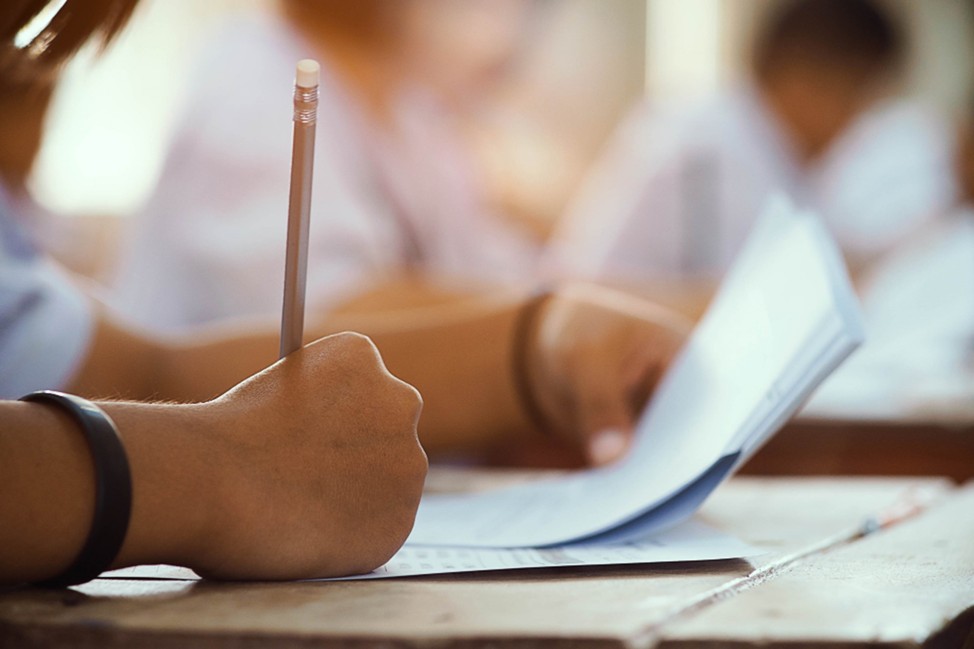 closeup hand student holding pencil taking exam classroom with stress education test